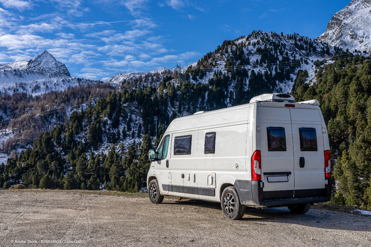 Ein Wohnmobil steht vor verschneiter Bergkulisse und bietet naturnahes Reisen auf einem Wohnmobilstellplatz Schweiz in den Alpen.